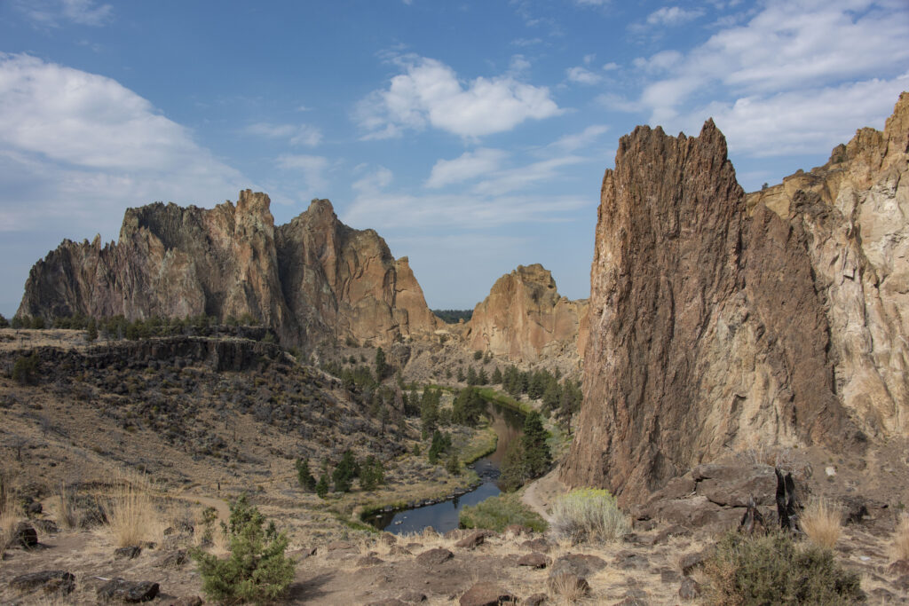 Dramatic rock formations above winding river with trees rugged terrain vibrant blue sky wallpaper