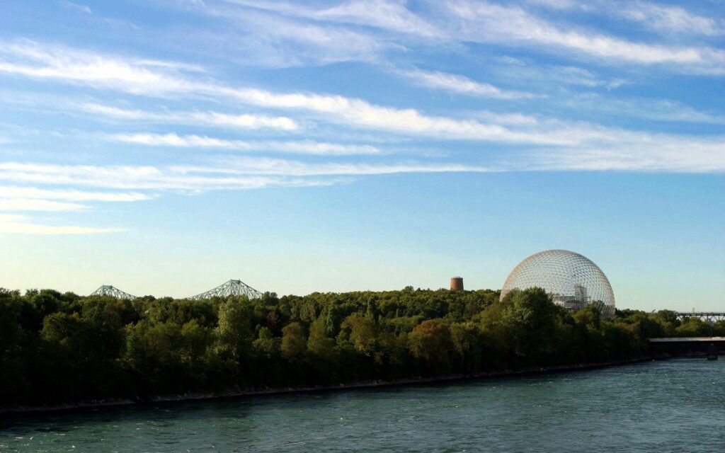 Serene riverside with lush trees gentle flowing river blue sky wispy clouds geodesic dome wallpaper