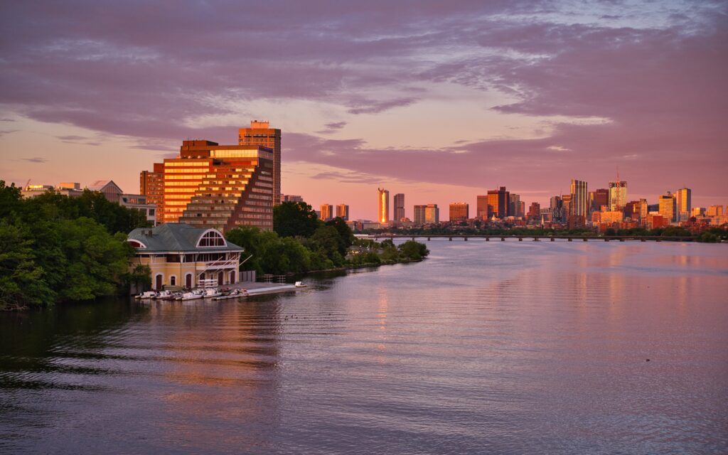 Serene Sunset Riverside Wallpaper: House, Trees, and Skyline View