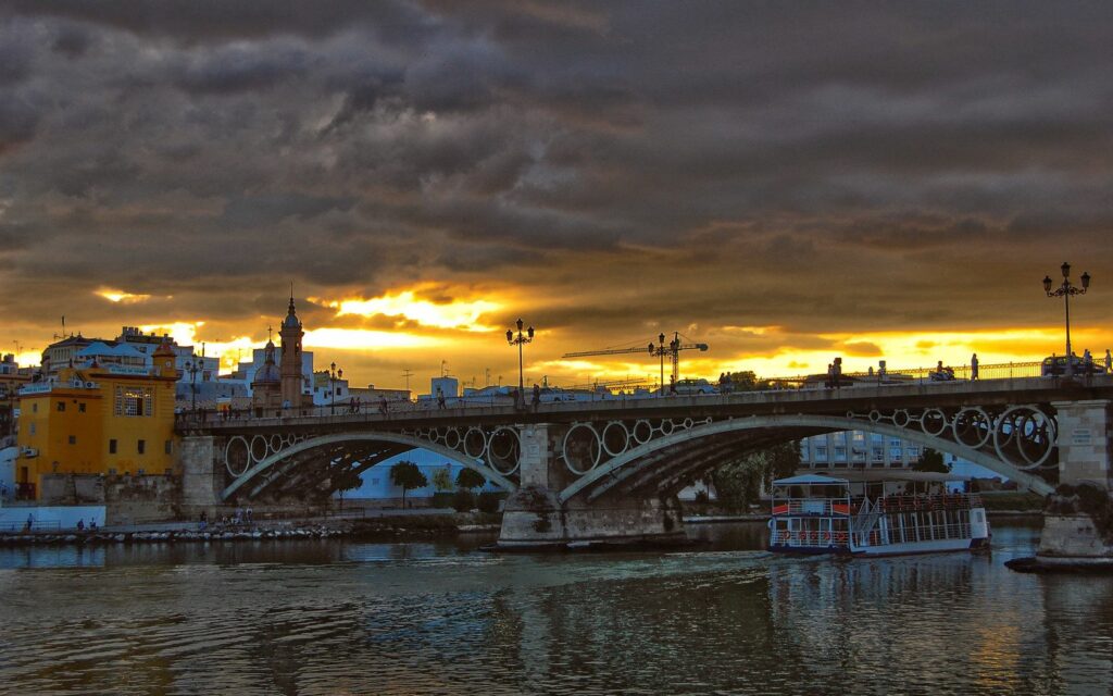 Serene Sunset Riverside Wallpaper with Historic Bridge & Charming Boats
