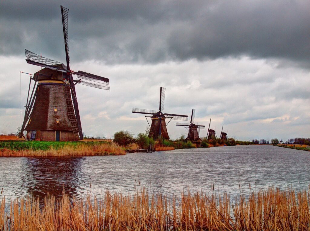 Serene Riverside Wallpaper: Historic Windmills & Dramatic Sky