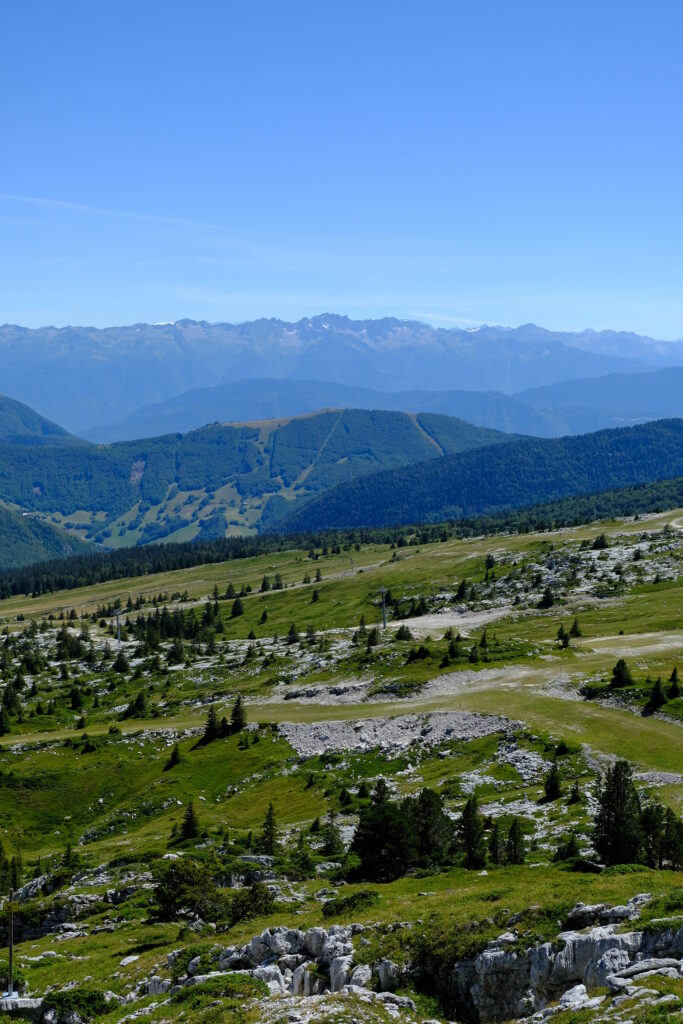 Rolling hills and rugged mountains with lush greenery under clear blue sky wallpaper background