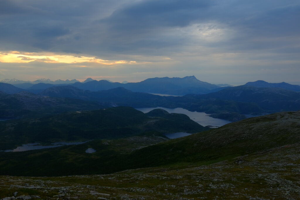Serene landscape of rolling green mountains and calm lakes under a dramatic evening sky wallpaper