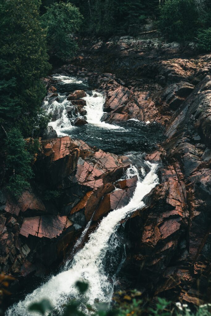 Rugged red rocks and flowing river in a lush green gorge nature wallpaper background