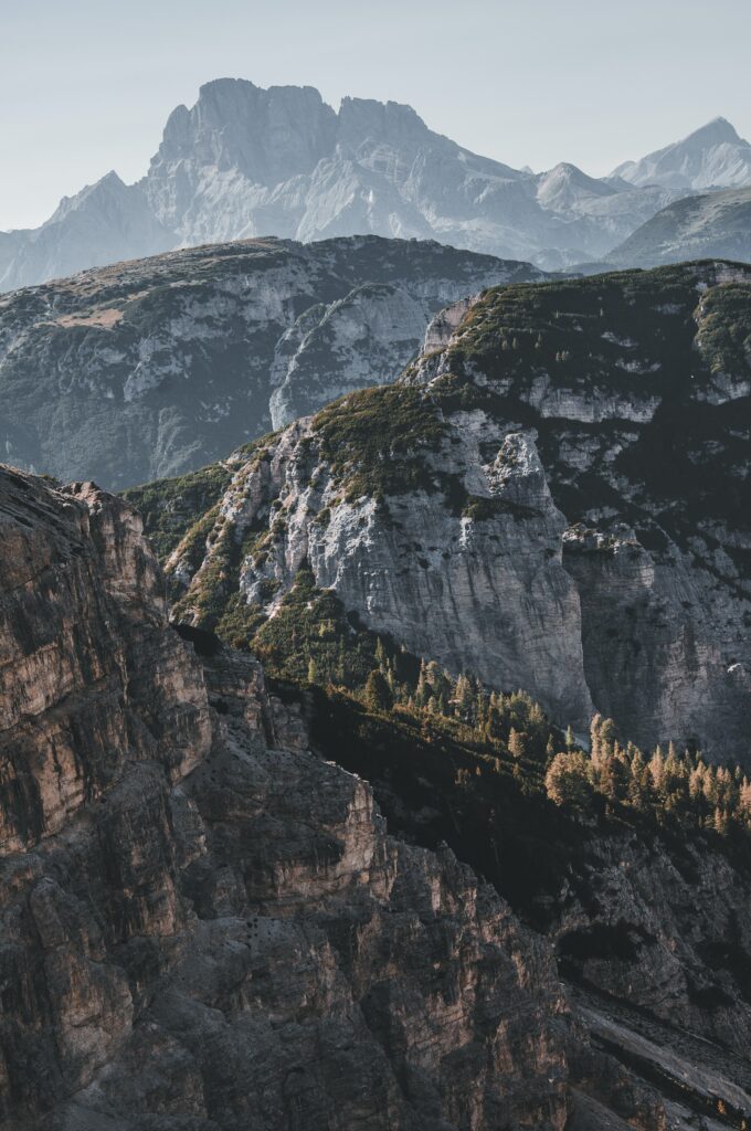 Rugged mountain peaks and layered rocky cliffs with muted earth tones and subtle greenery wallpaper