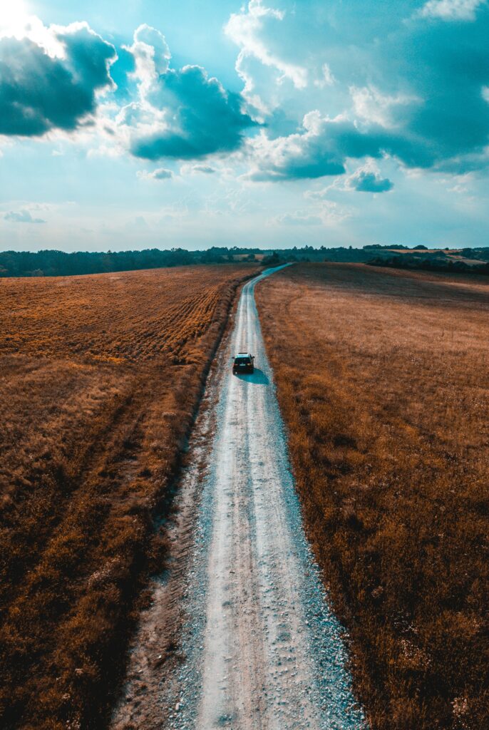 Serene rural road through golden fields near Timisoara Romania car driving under cloudy sky wallpaper