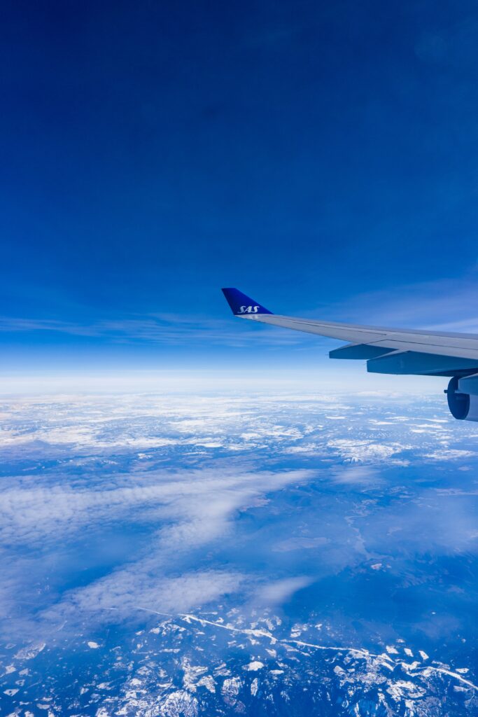 SAS airplane wing over deep blue sky with clouds and expansive aerial landscape view wallpaper