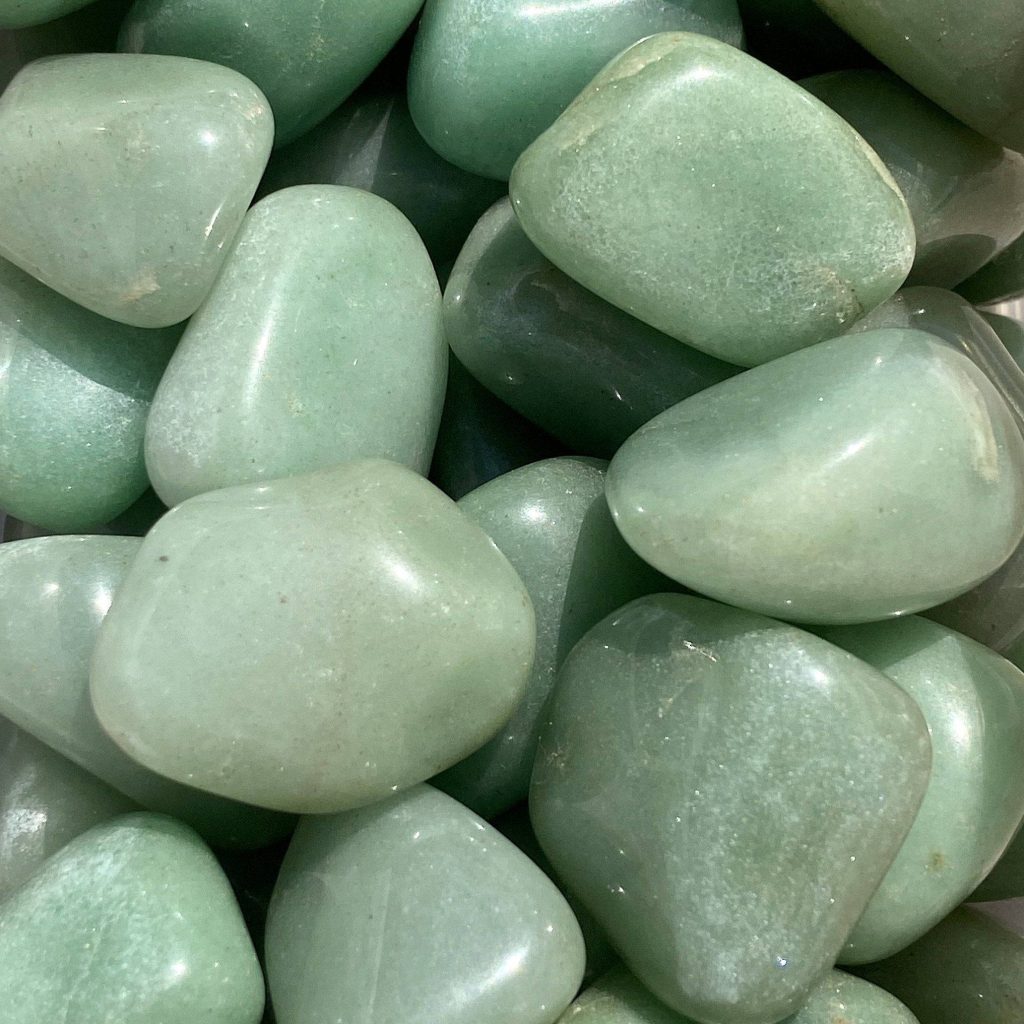 Glossy sage green tumbled stones close up polished smooth semi translucent earthy wallpaper background