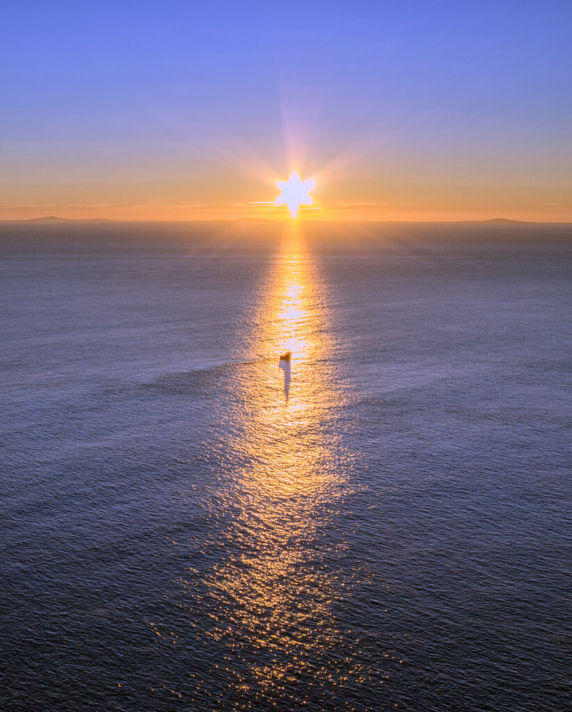Sunset over calm Scottish sea with golden light reflecting on water and clear sky wallpaper