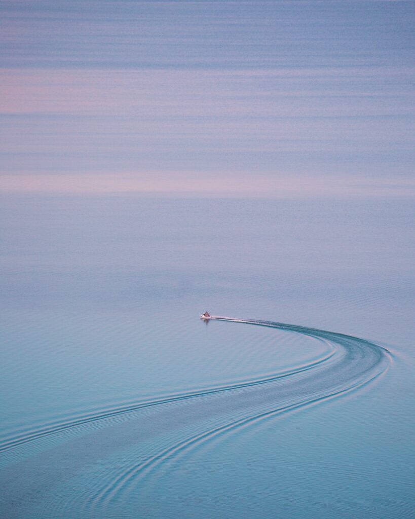 Serene sea ripples and pastel sky with distant boat over calm blue waters near Tbilisi wallpaper