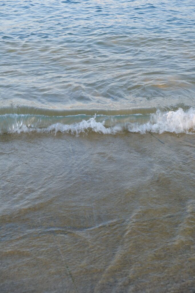 Serene sea wallpaper with gentle waves soft ripples blue and sandy hues peaceful shore background
