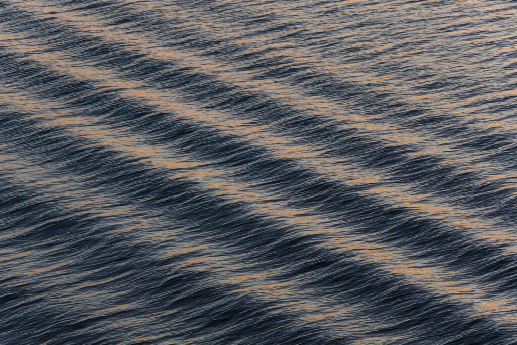 Serene deep blue sea wallpaper with gentle waves soft light reflections and warm natural tones