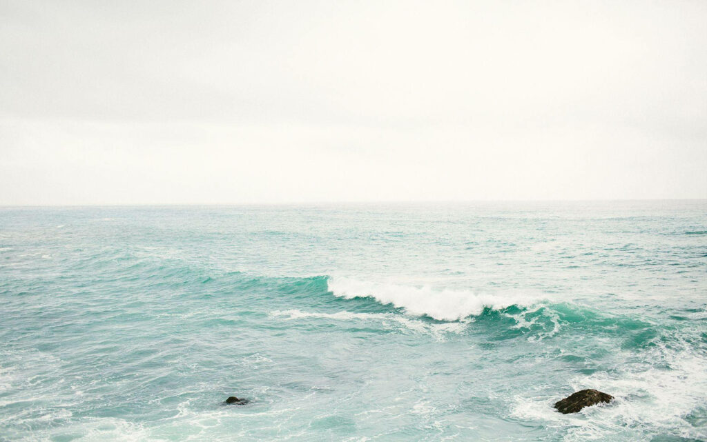 Tranquil Coastal Beauty: Capturing Refreshing Ocean Waves and Grey Sky for Macbook Aesthetic Background Wallpaper