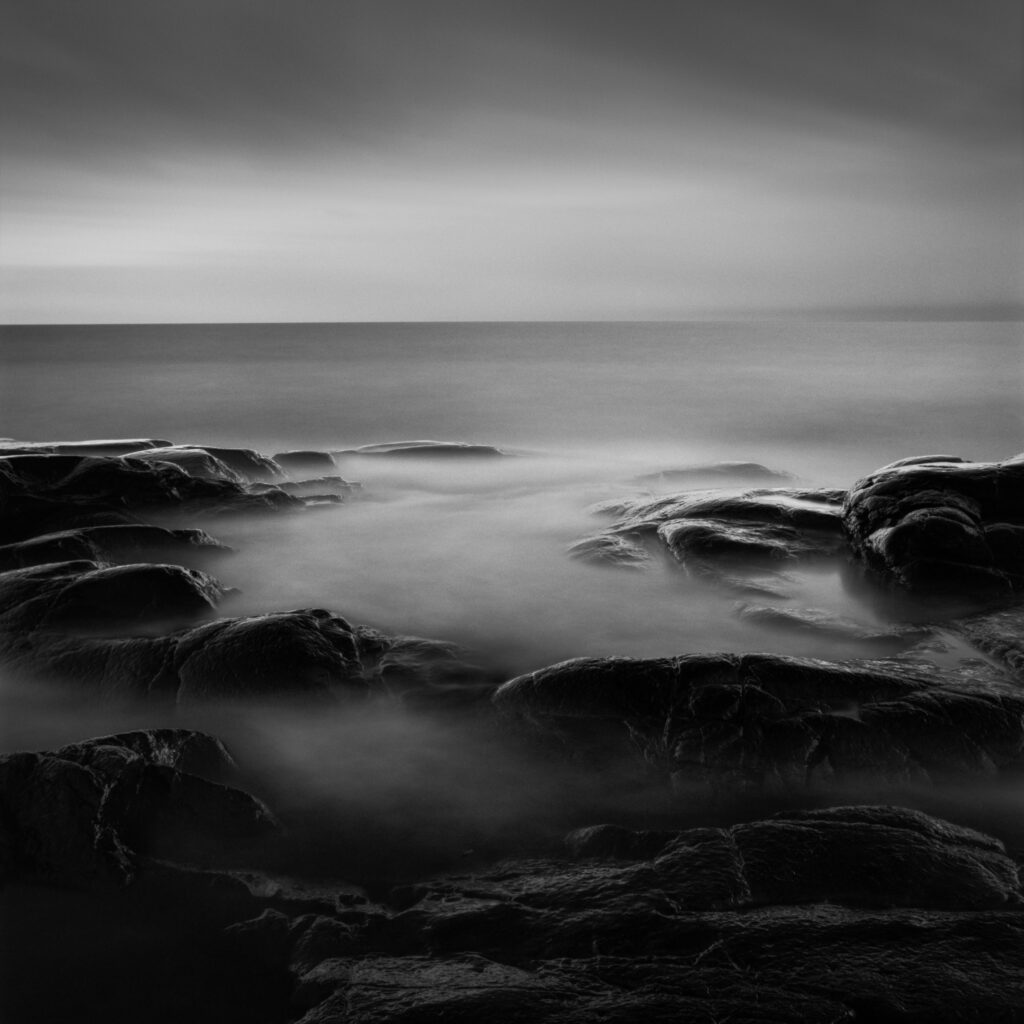 Serene Seascape Wallpaper with Misty Waves and Dark Rocks