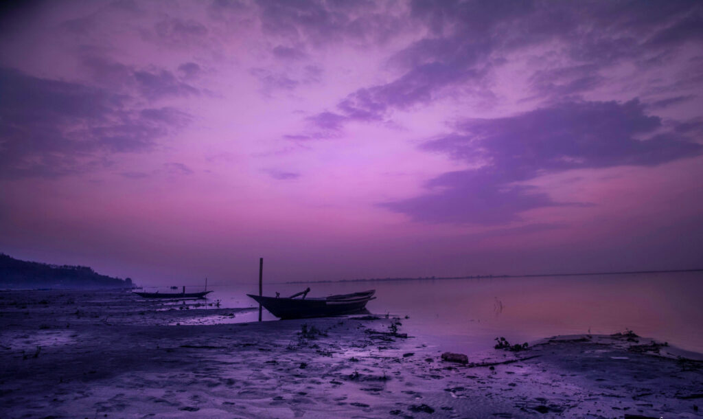 Serene Seaside Majesty: A Captivating Boat Embraced by the Enchanting Dark Purple Aesthetic Wallpaper