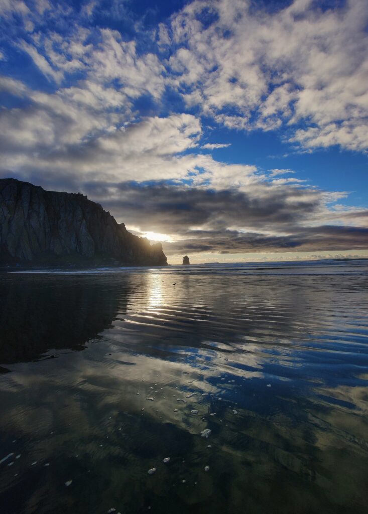 Serene seaside sunset wallpaper with dramatic blue and gold clouds over rocky coast and waves
