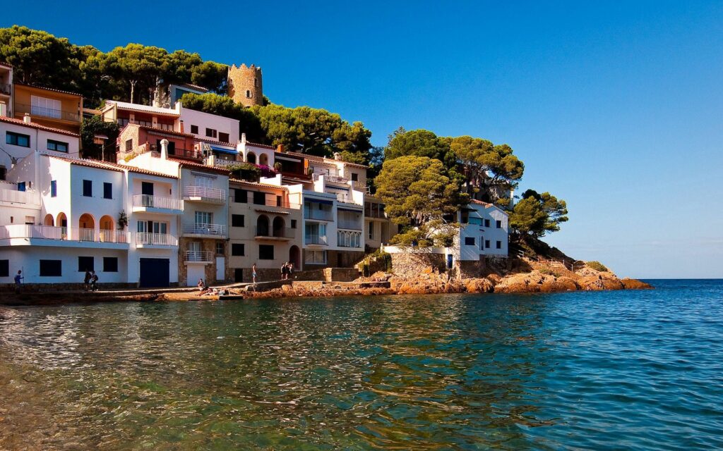 Tranquil Seaside Village Wallpaper: Serene Shoreline & White Buildings