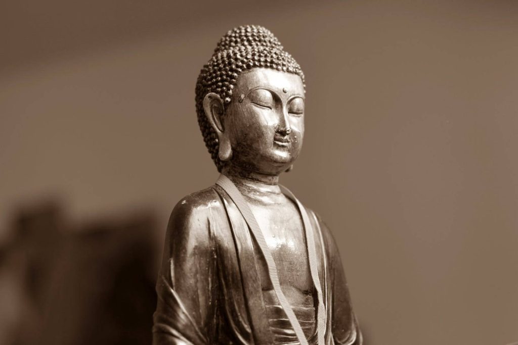 Sepia-toned Gautam Buddha ceramic statue close-up with serene meditative expression wallpaper