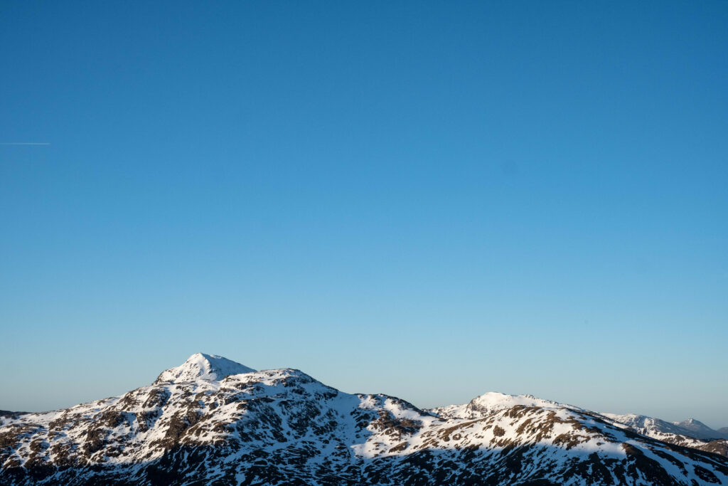 Snow-capped mountain peaks under clear blue sky showcasing serene natural landscape wallpaper