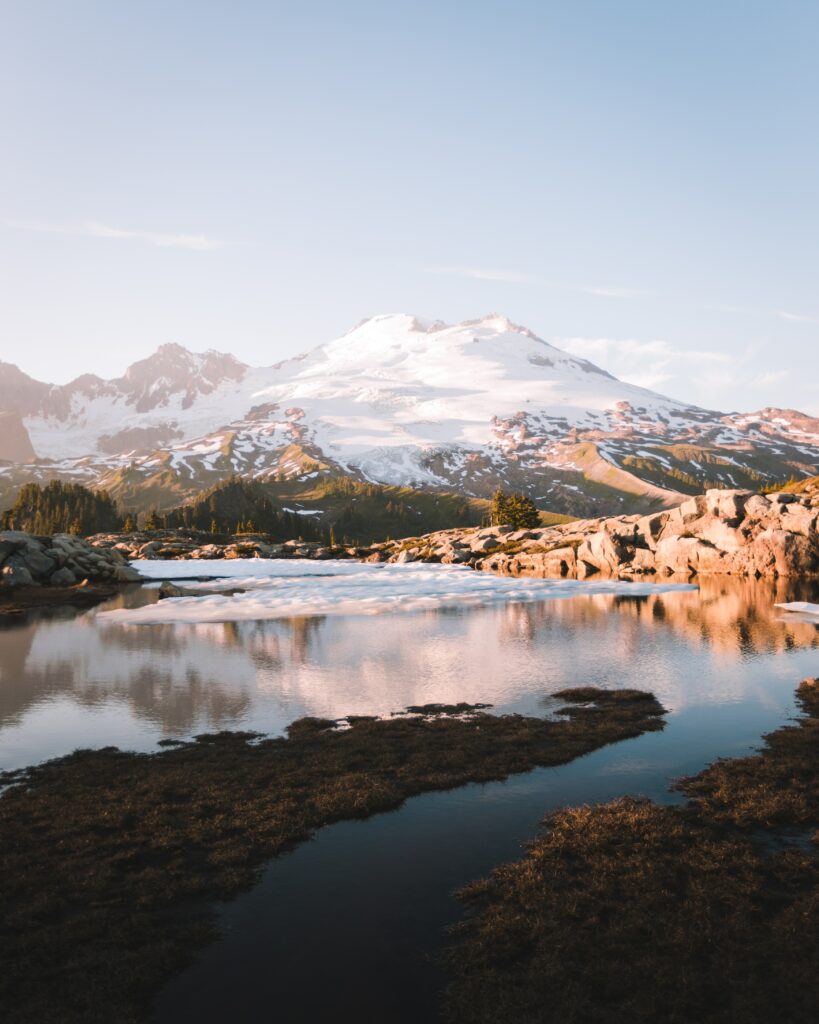 Serene mountain landscape with snow-capped peak reflecting in lake at golden sunrise wallpaper