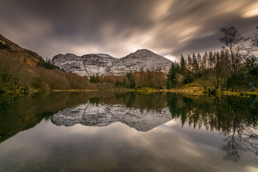 Serene landscape wallpaper with snow-capped mountains dense forest and tranquil reflective lake