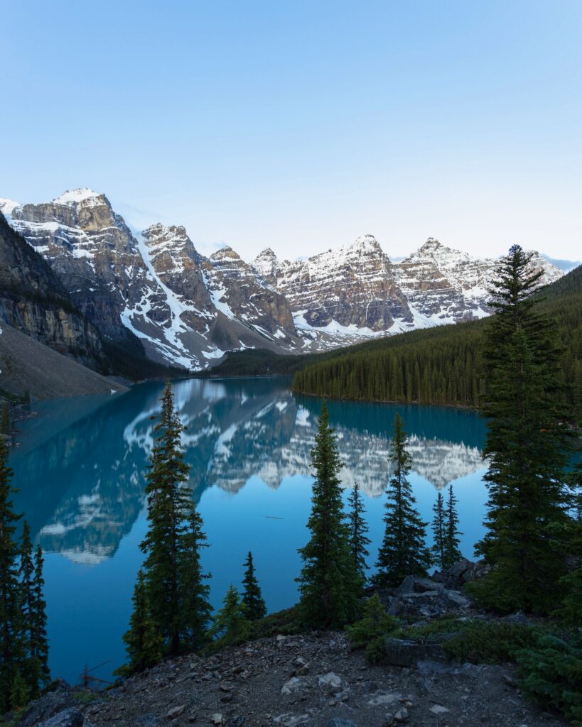 Snow-capped mountain landscape reflected in clear lake with evergreen trees winter morning wallpaper