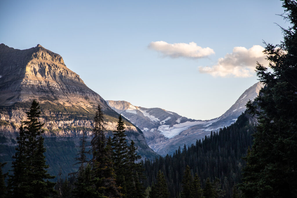 Serene mountain landscape with snow-capped peaks forested slopes and warm sunlight wallpaper background
