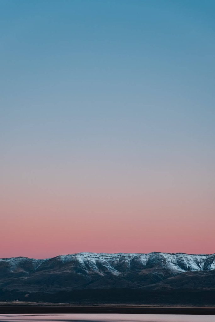 Snow-capped mountain range at twilight with soft blue to pink gradient minimalist phone wallpaper