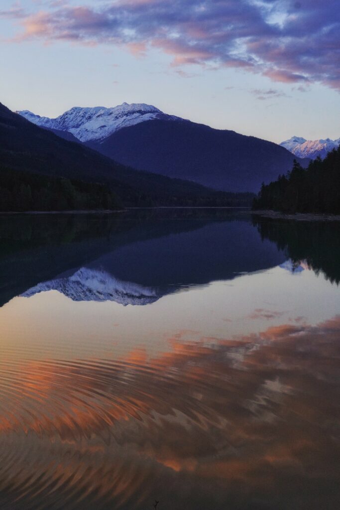 Serene snow-capped mountains lush forests tranquil lake reflecting pastel sky natural landscape wallpaper