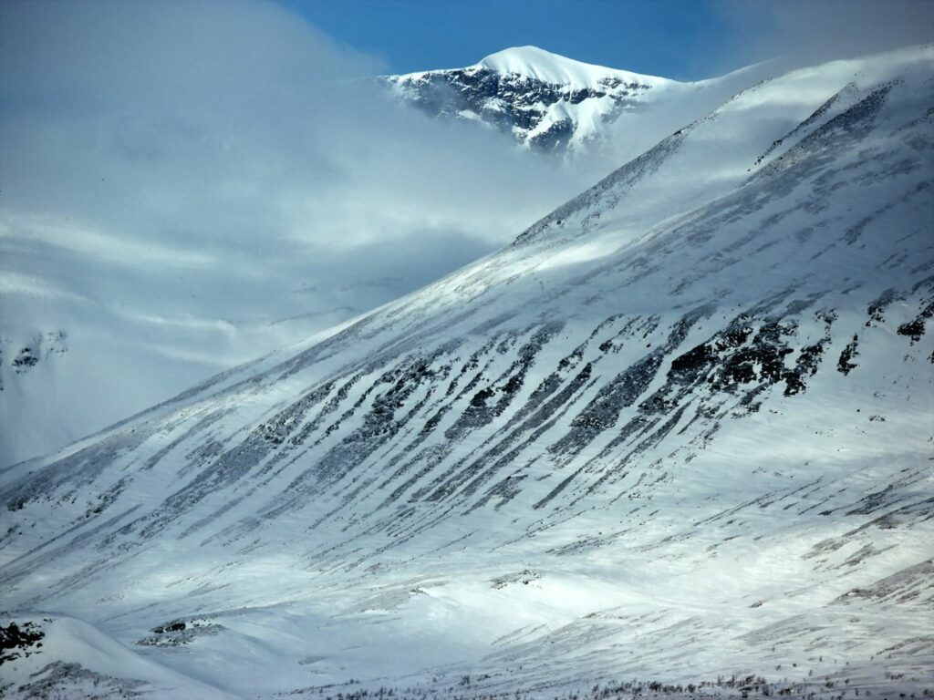 Snowy towering mountains with rugged slopes misty fog serene winter landscape wallpaper background