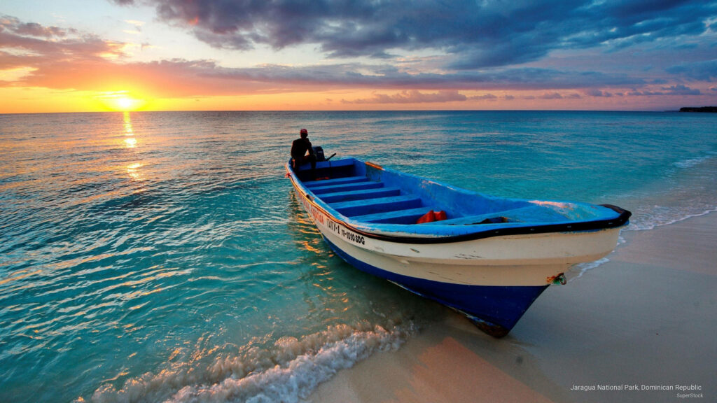 Serenity at Dusk: Captivating Coastal Scene featuring an Unoccupied Blue and White Boat amidst Turquoise Waters Wallpaper