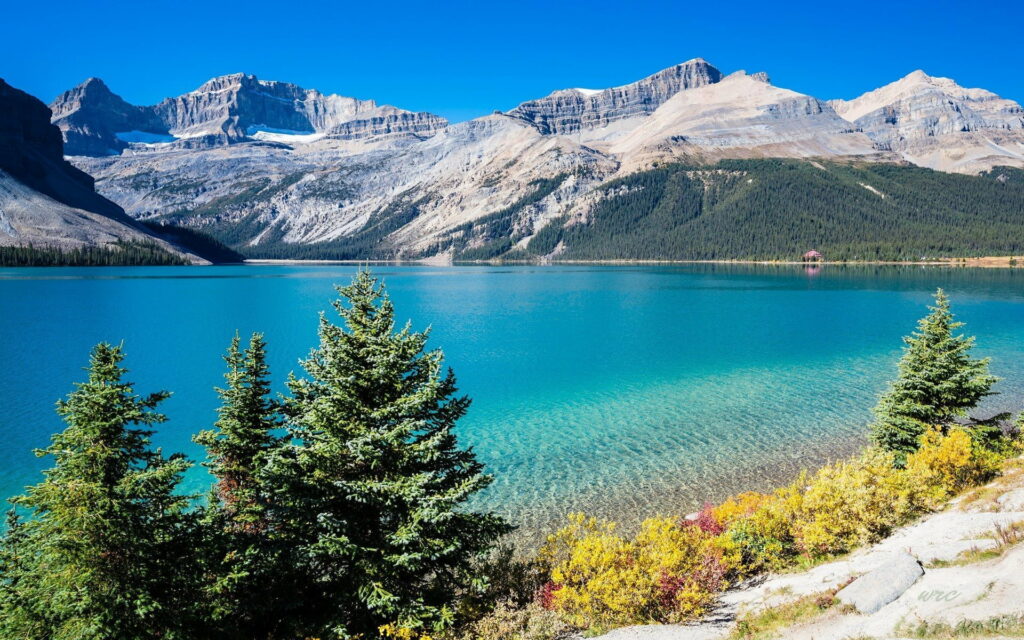 A Serene Spring Splendor: Majestic Mountains, Tranquil Lake, and Lush-tree Embellished HD Wallpaper