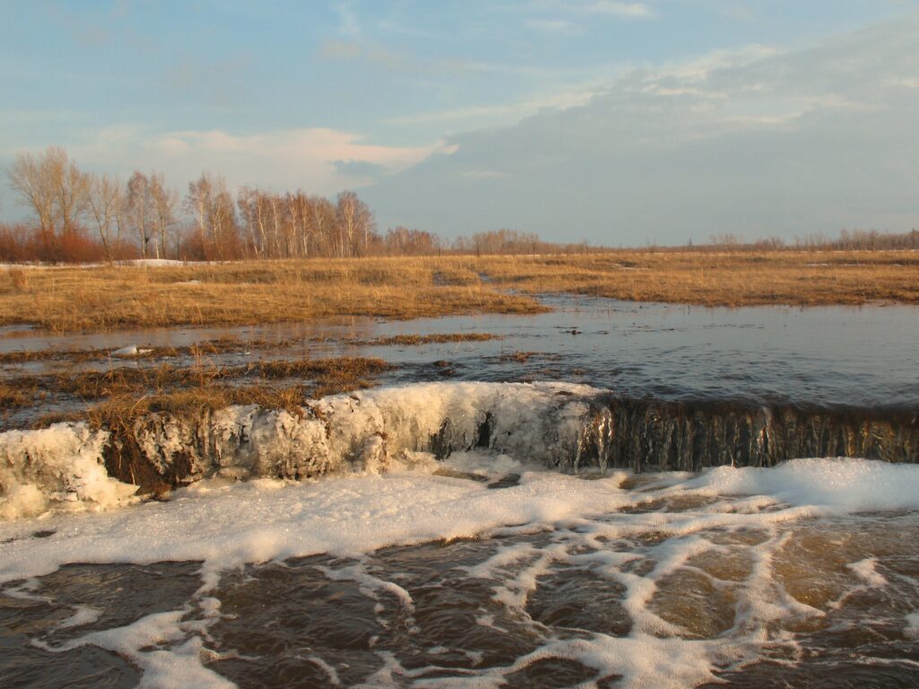 Melting floodwaters over grassy fields in Kokshetau spring landscape under soft April sky Wallpaper
