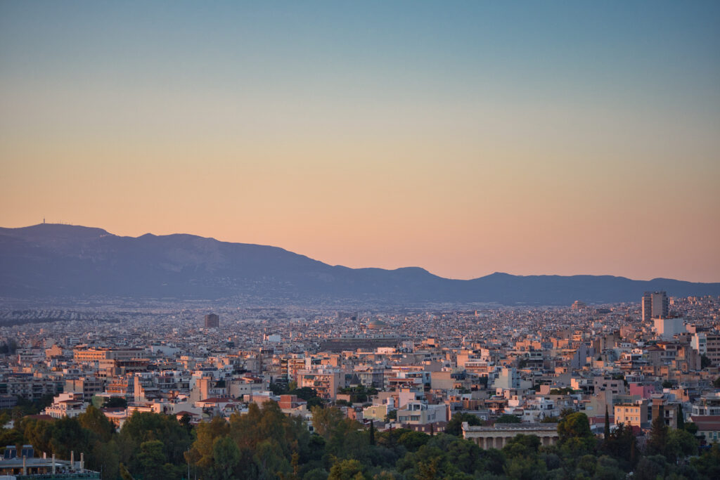 Serene Sunset Cityscape Wallpaper: Buildings, Trees & Mountains