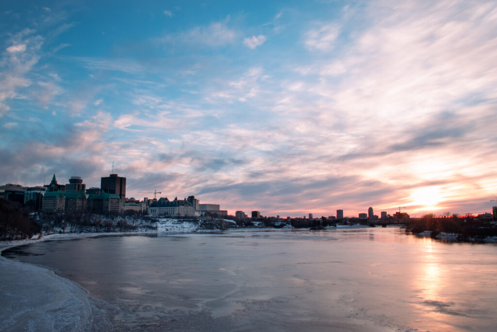 Serene Sunset Cityscape Wallpaper with Reflective Frozen Lake