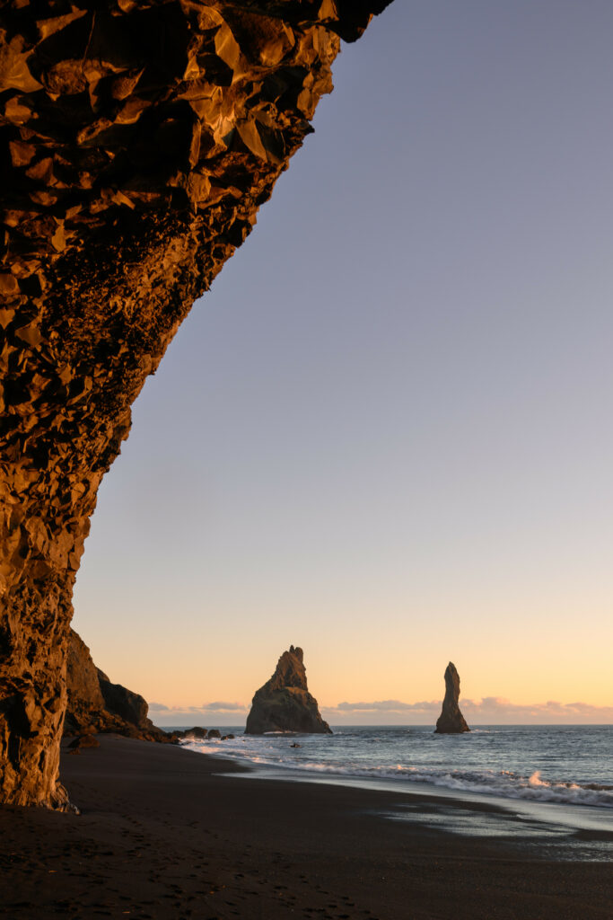 Serene coastal sunset with rugged sea rocks and rocky overhang bathed in golden light wallpaper