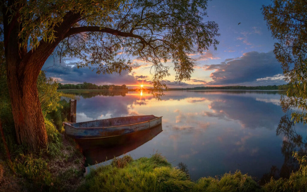 Serene Sunset Lake Wallpaper with Rustic Boat & Lush Greenery