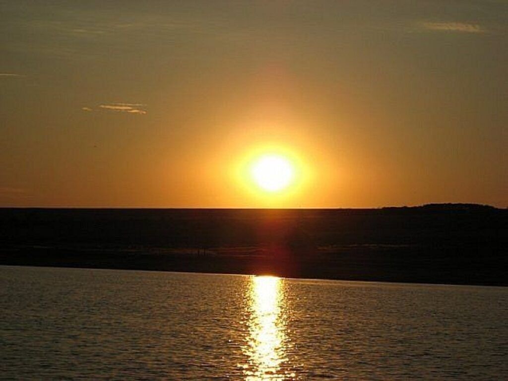Serene sunset over calm river with golden sky reflections peaceful natural landscape wallpaper