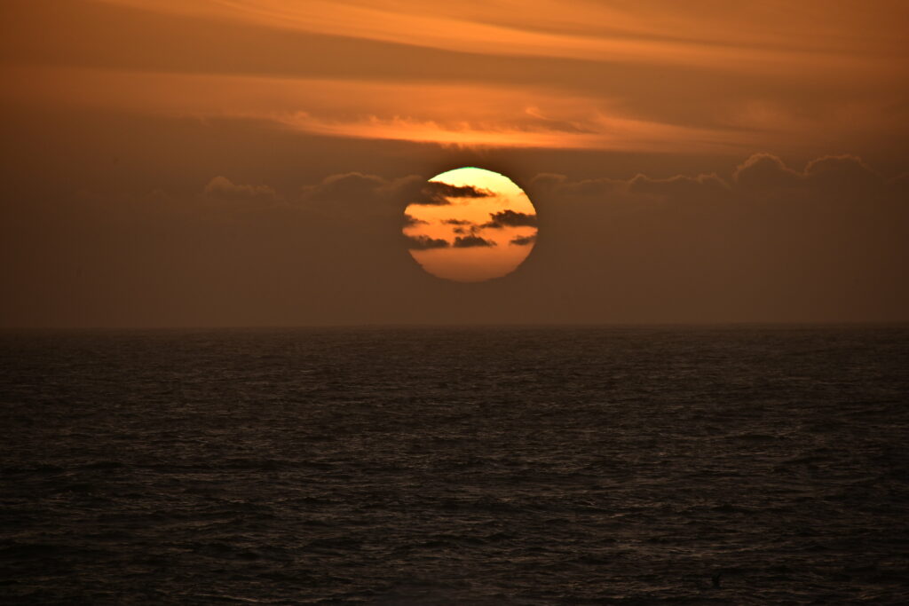 Fiery sunset over tranquil sea with orange gold sky reflecting on calm rippling water wallpaper