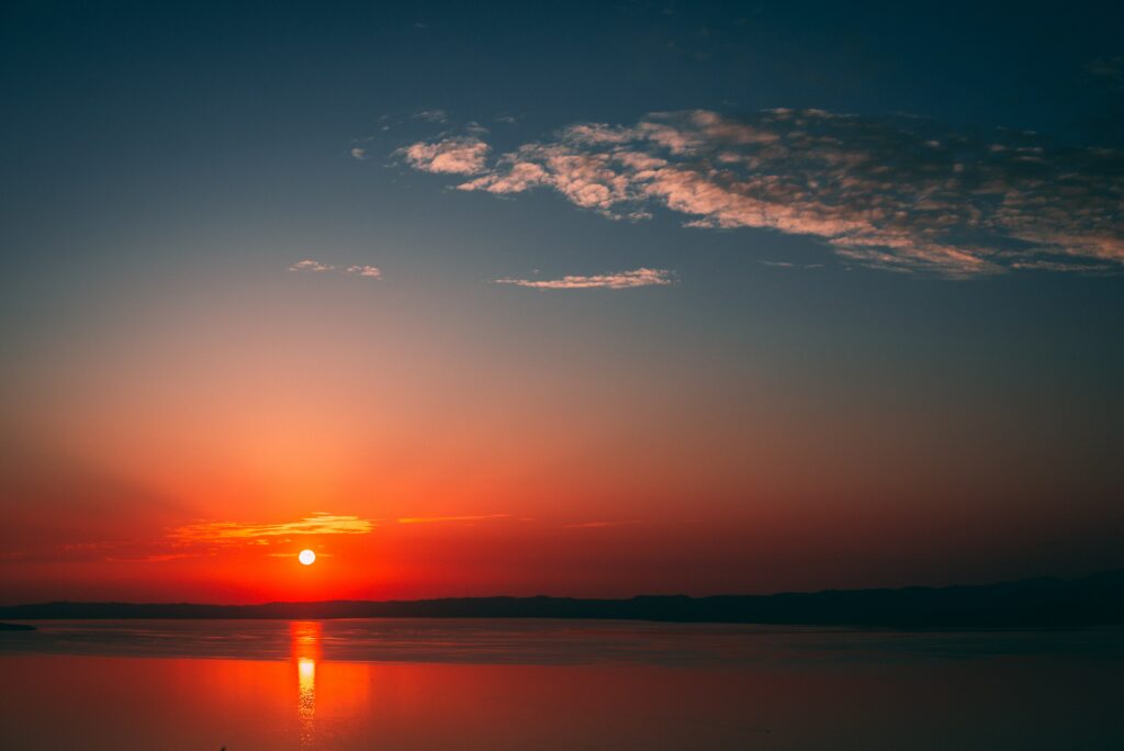 Serene sea sunset wallpaper with warm orange red hues and golden reflection on calm water