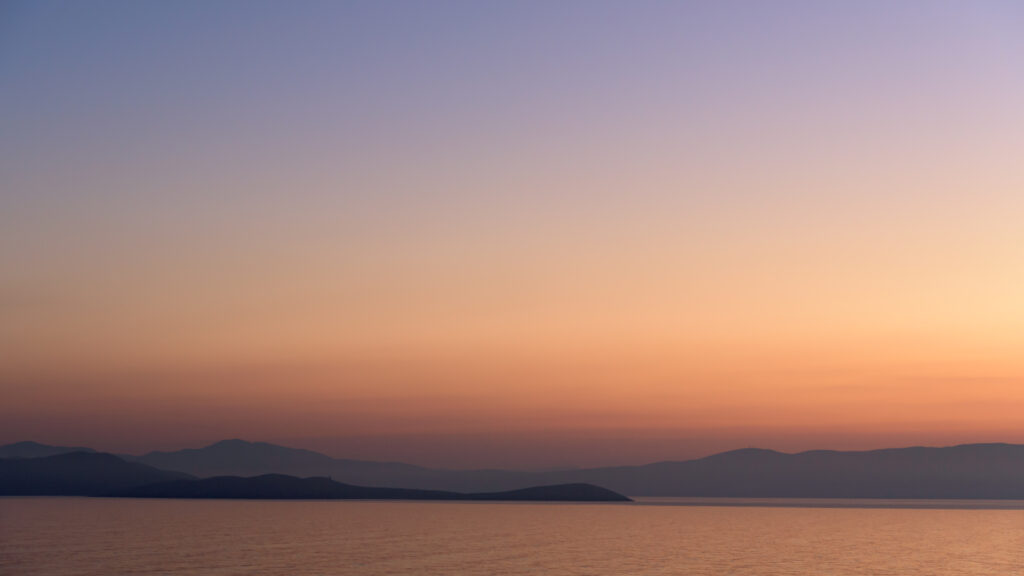 Serene sea sunset wallpaper with orange purple sky foggy mountains calm peaceful nature scene