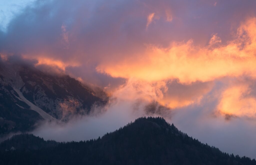 Dramatic orange and pink sunset over misty mountains and foggy forested ridge landscape wallpaper