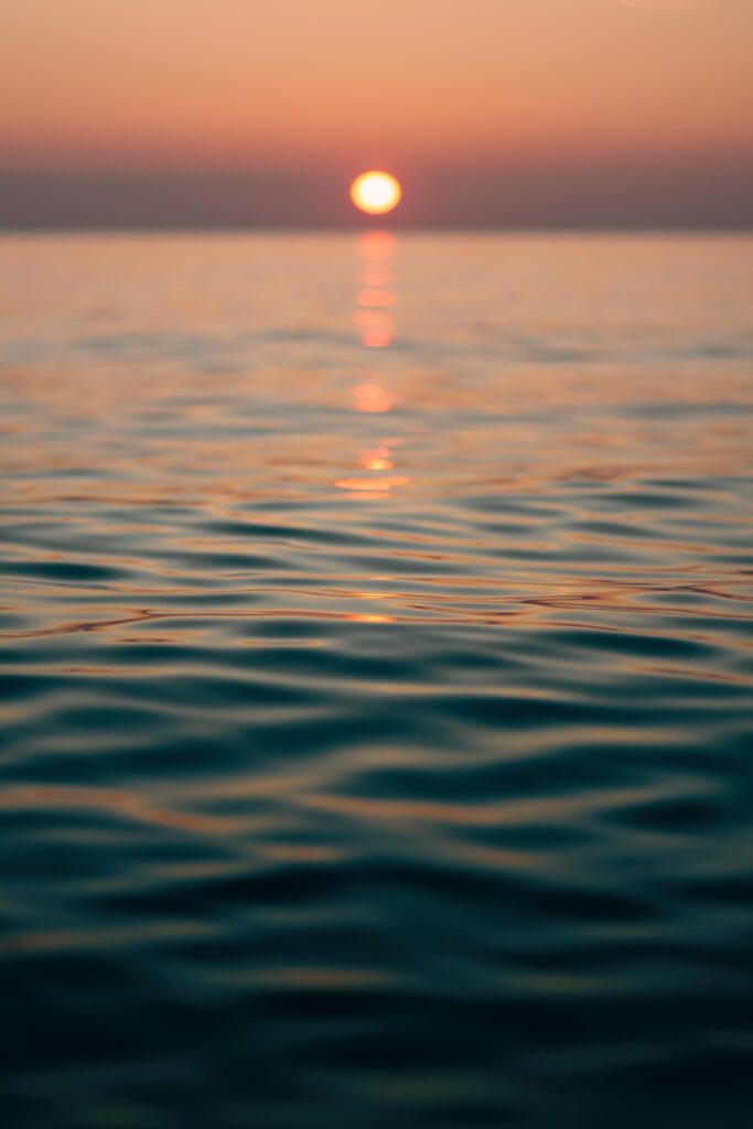 Serene sunset over calm rippling waves reflecting warm orange and blue hues dusk wallpaper
