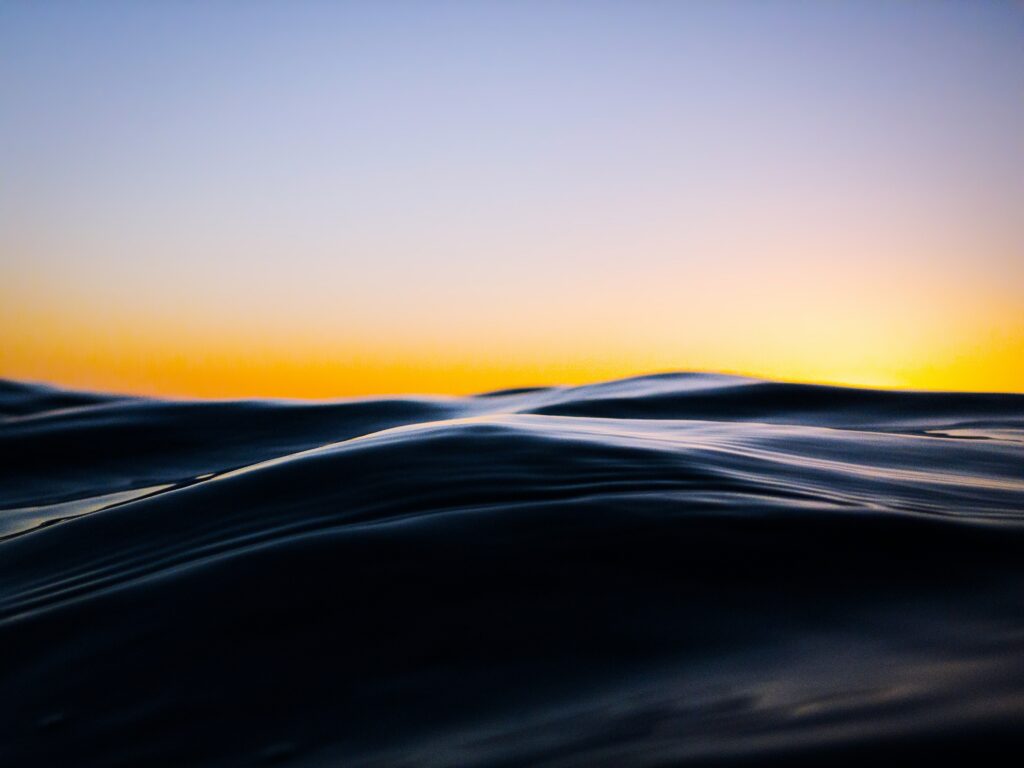 Sunset over smooth rolling dunes with golden and blue hues for calming wallpaper background