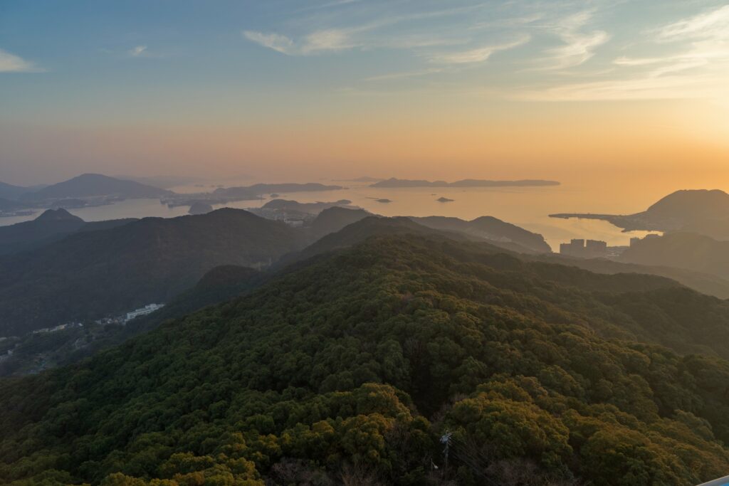 Sunset over rolling green hills rugged mountains and tranquil sea with soft pastel horizon colors Wallpaper