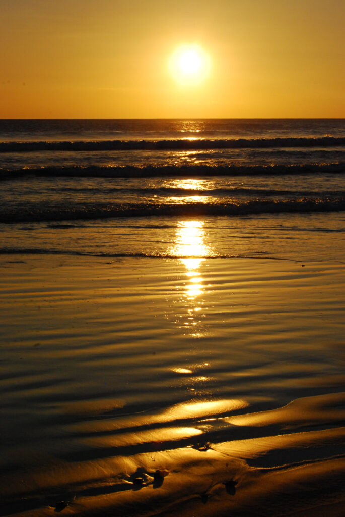 Serene sunset over calm sea with golden sun and shimmering waves on smooth sand wallpaper