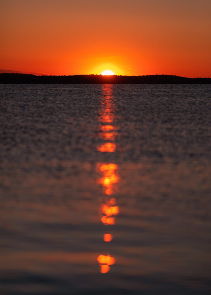Breathtaking sunset wallpaper with warm orange red tones reflecting calm water horizon glare