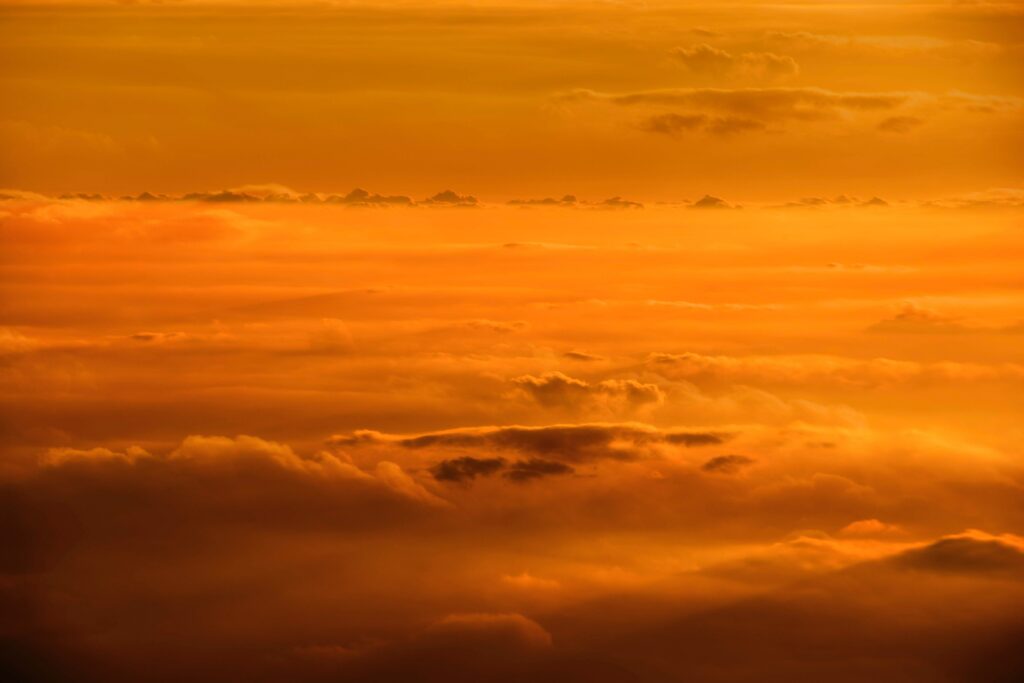 Serene sunset sky with soft clouds glowing yellow and gold creating a tranquil wallpaper background