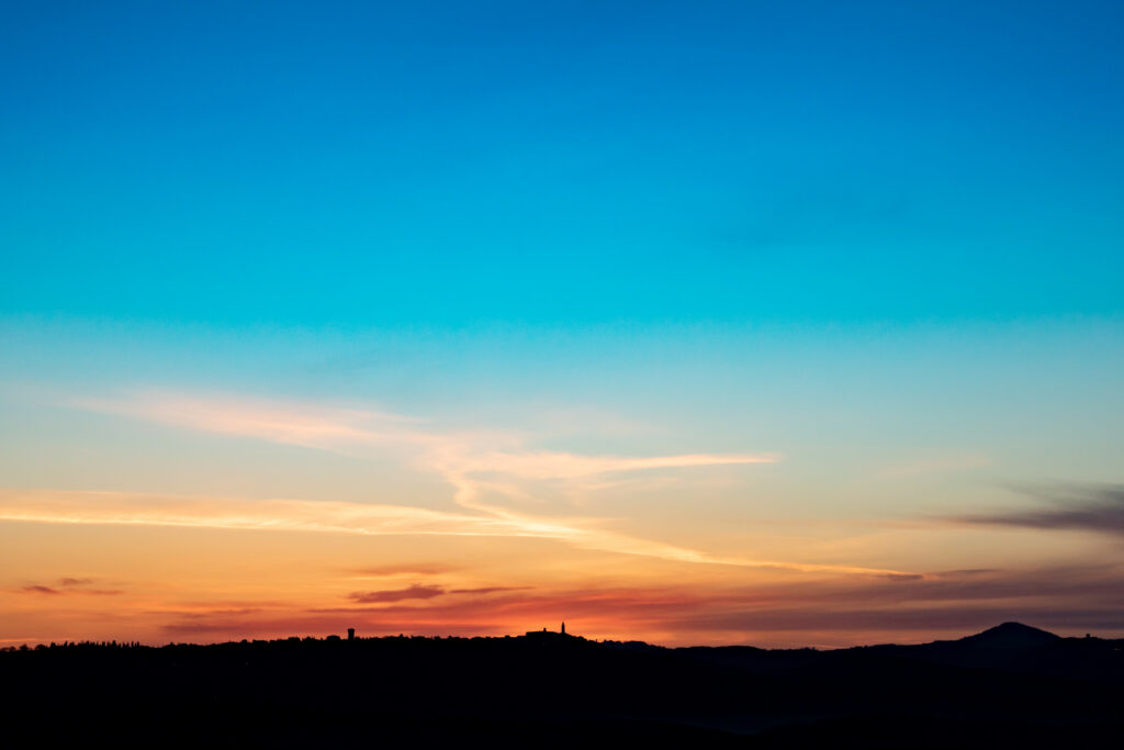 Serene sunset sky with vibrant blue orange gold gradients and silhouetted hills at dusk wallpaper