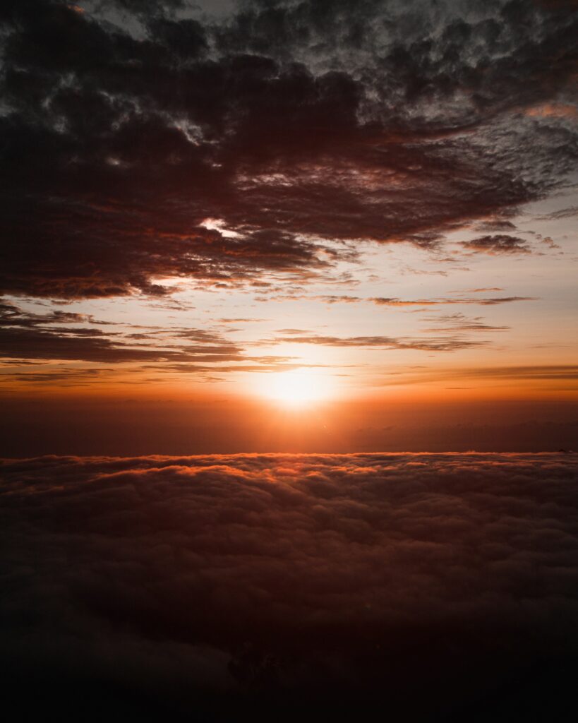 Serene sunset wallpaper with sun dipping below fluffy clouds in orange gold and dark tones